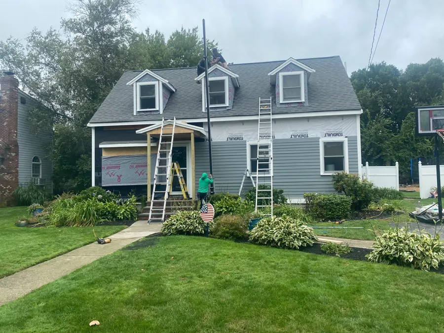 Crew finishing exterior renovation with a well-kept lawn