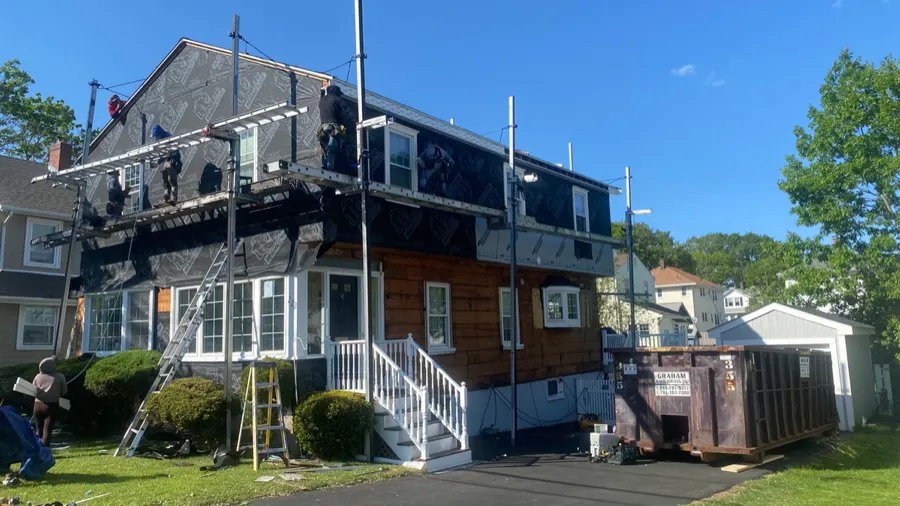 Shingle-style home under roofing and siding renovation